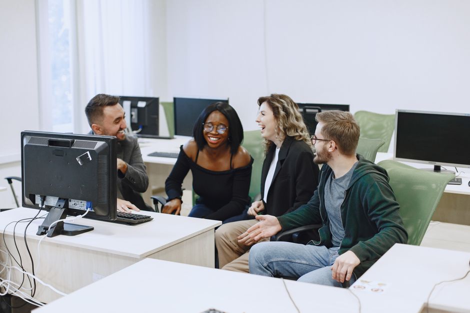 Teilnehmende arbeiten gemeinsam an einem Laptop im Kurs